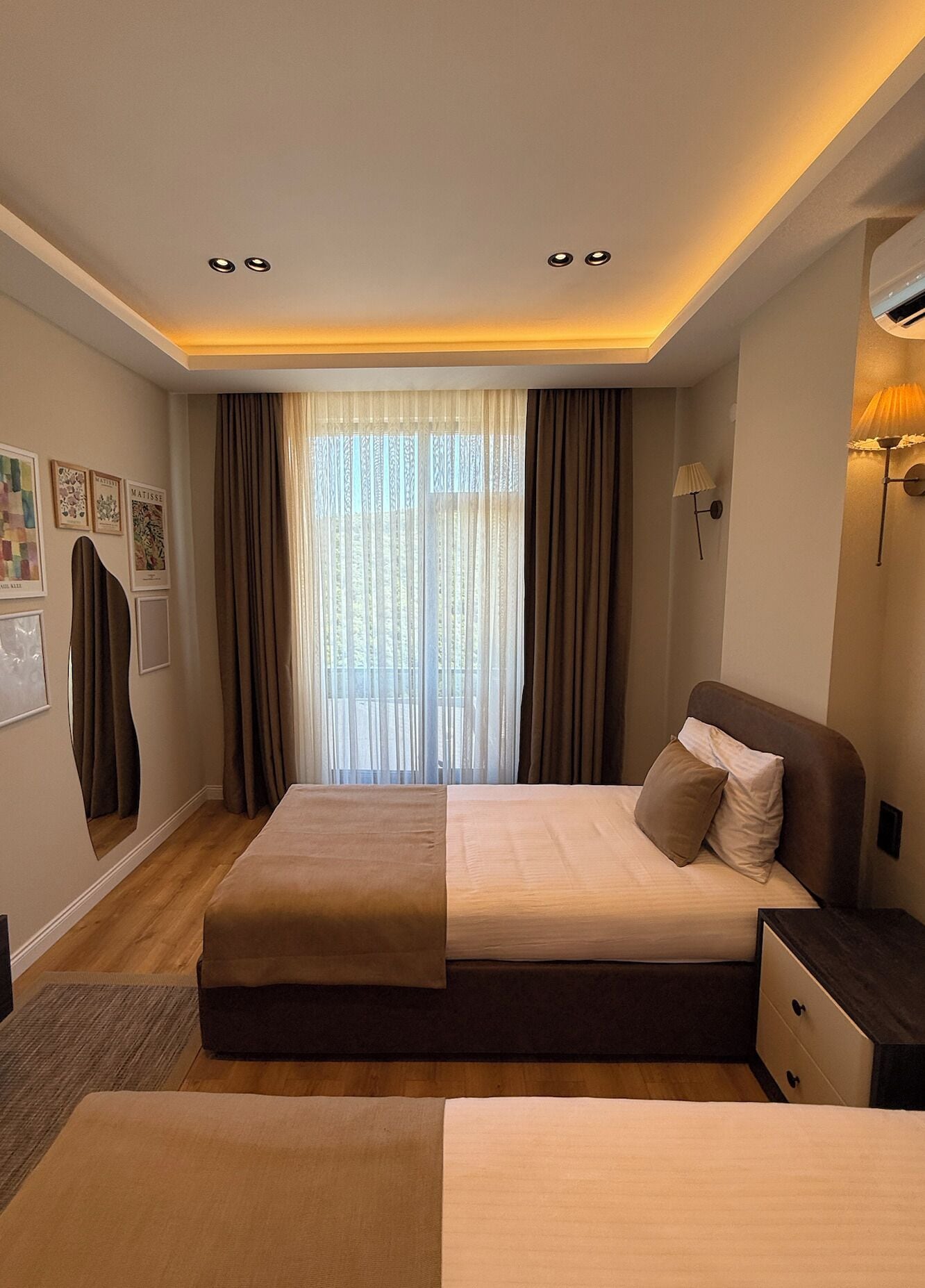 Un dormitorio moderno con una cama grande, una mesita de noche y una ventana con cortinas.