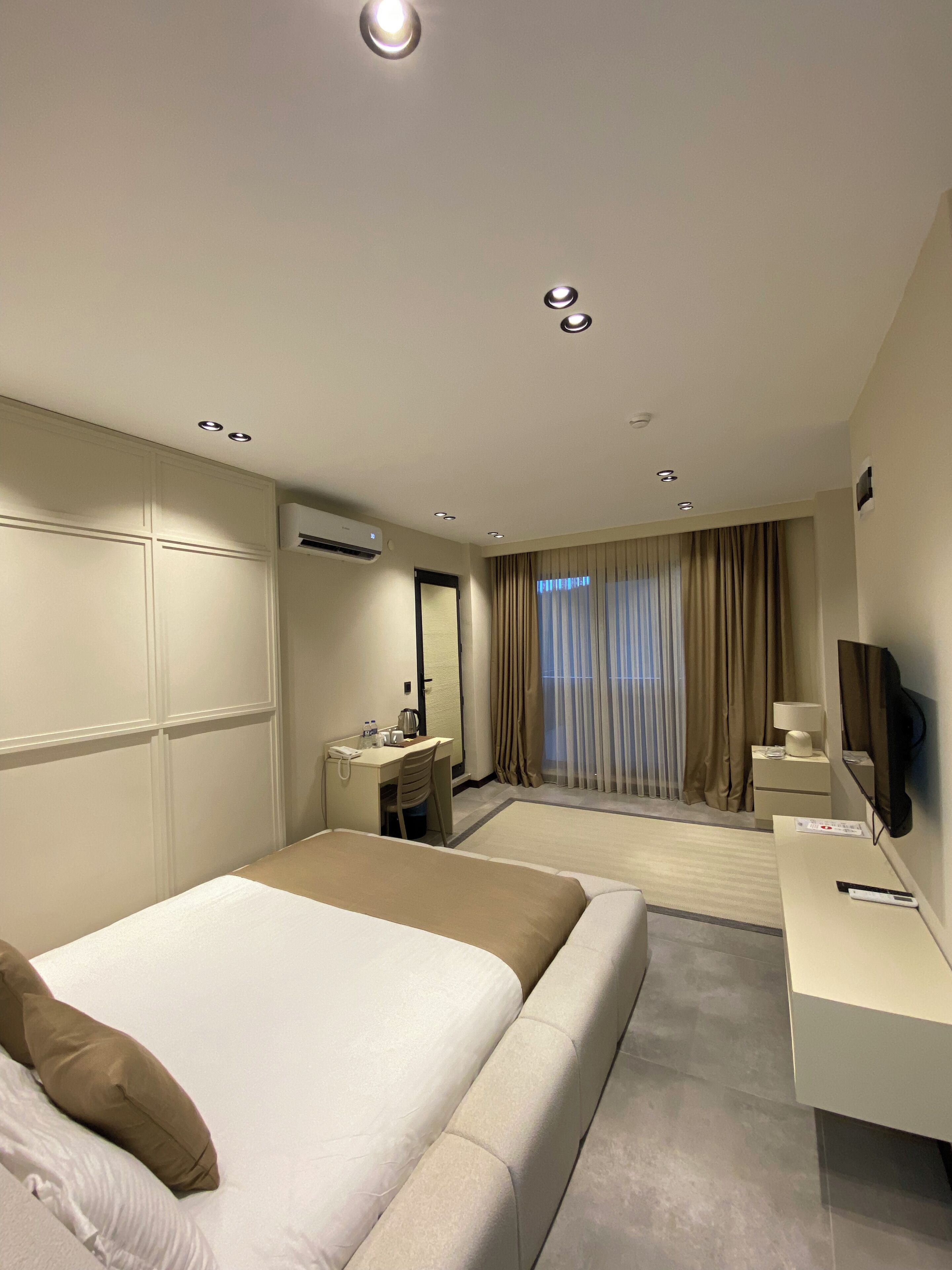 Une chambre d’hôtel avec un grand lit, un bureau avec une chaise, une télévision et un appareil de climatisation.