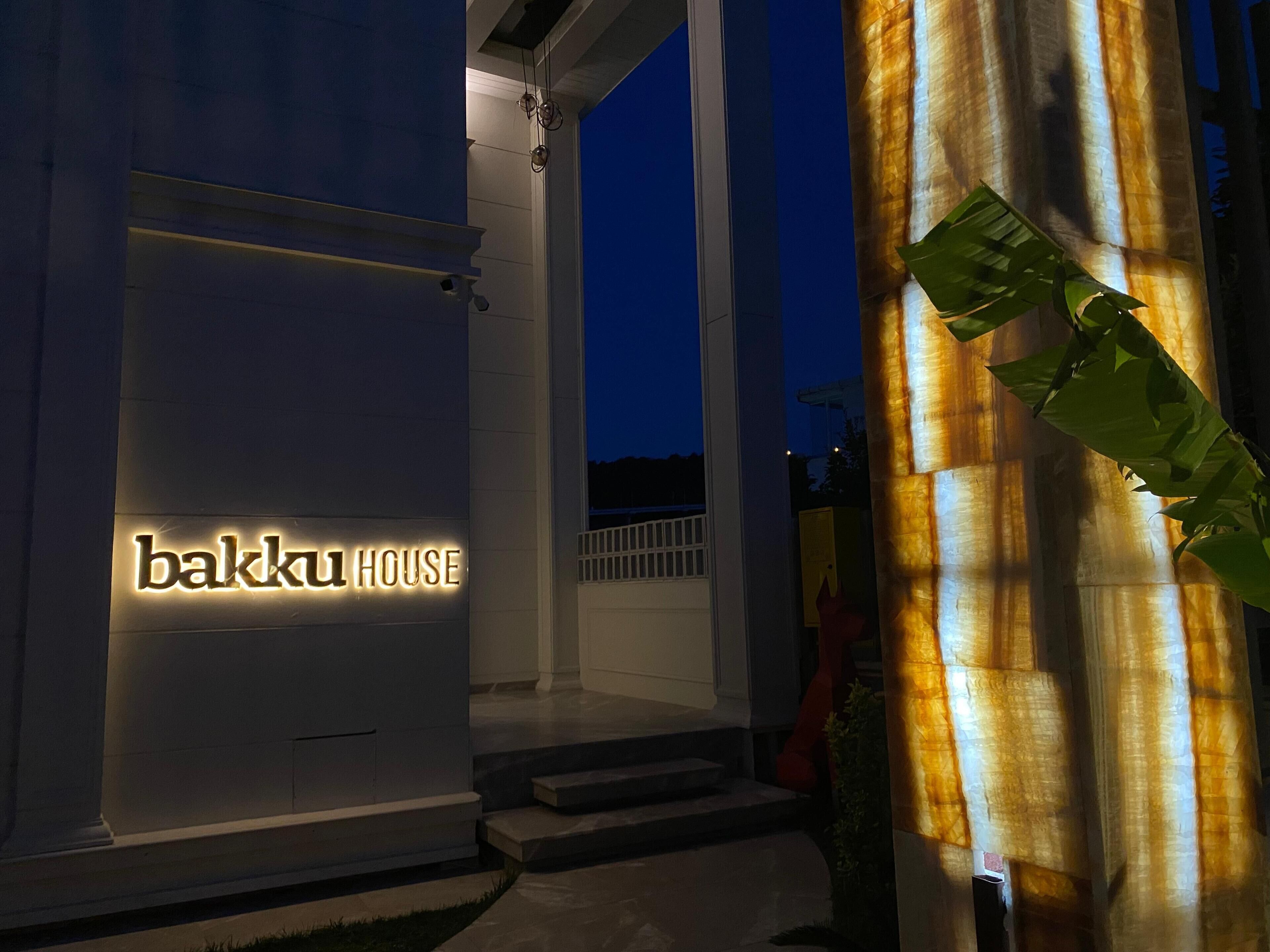 A building entrance with a sign reading 'bakku HOUSE' and a staircase leading up to the door.