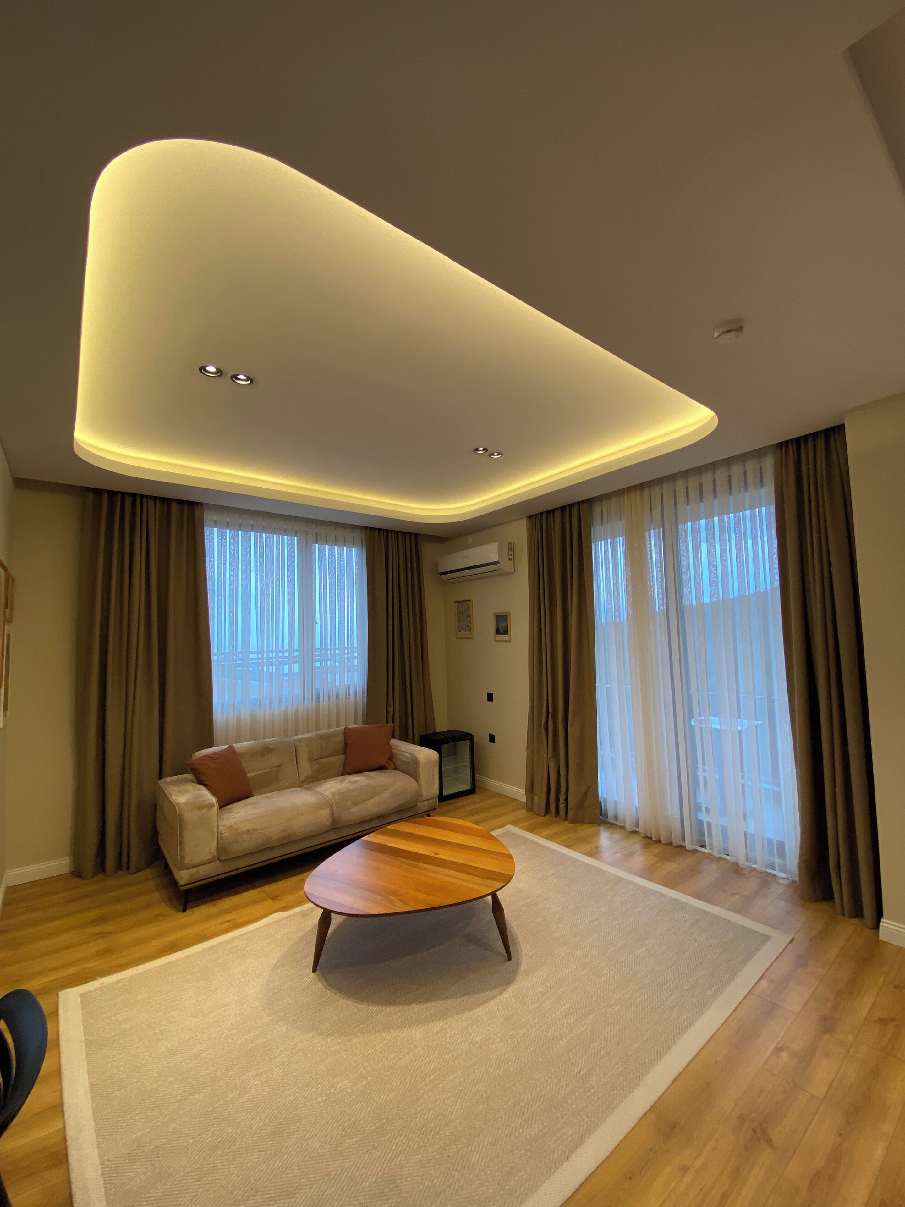 A modern living room with a sofa, a coffee table, and a ceiling light fixture.