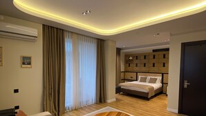 A modern hotel room with a sofa, a wooden coffee table, a bed, and a built-in wardrobe. - Bakku House (Atakum)