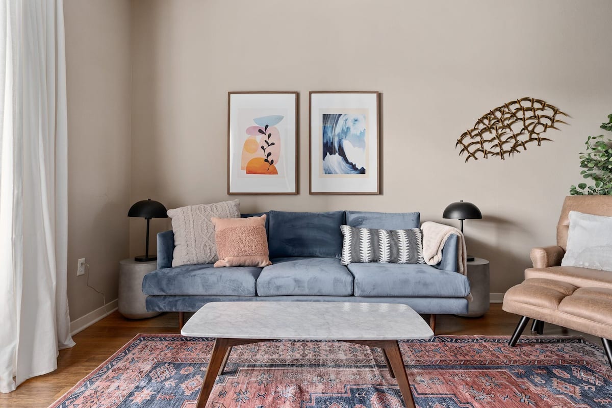 A living room with a blue sofa, two side tables, a coffee table, and a patterned rug.