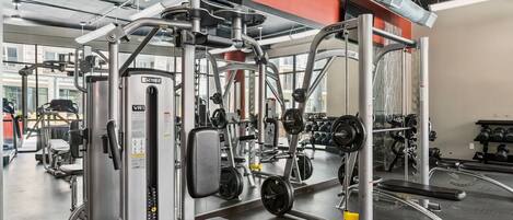 Ett gym med olika träningsmaskiner, speglar och utrustning för styrketräning.