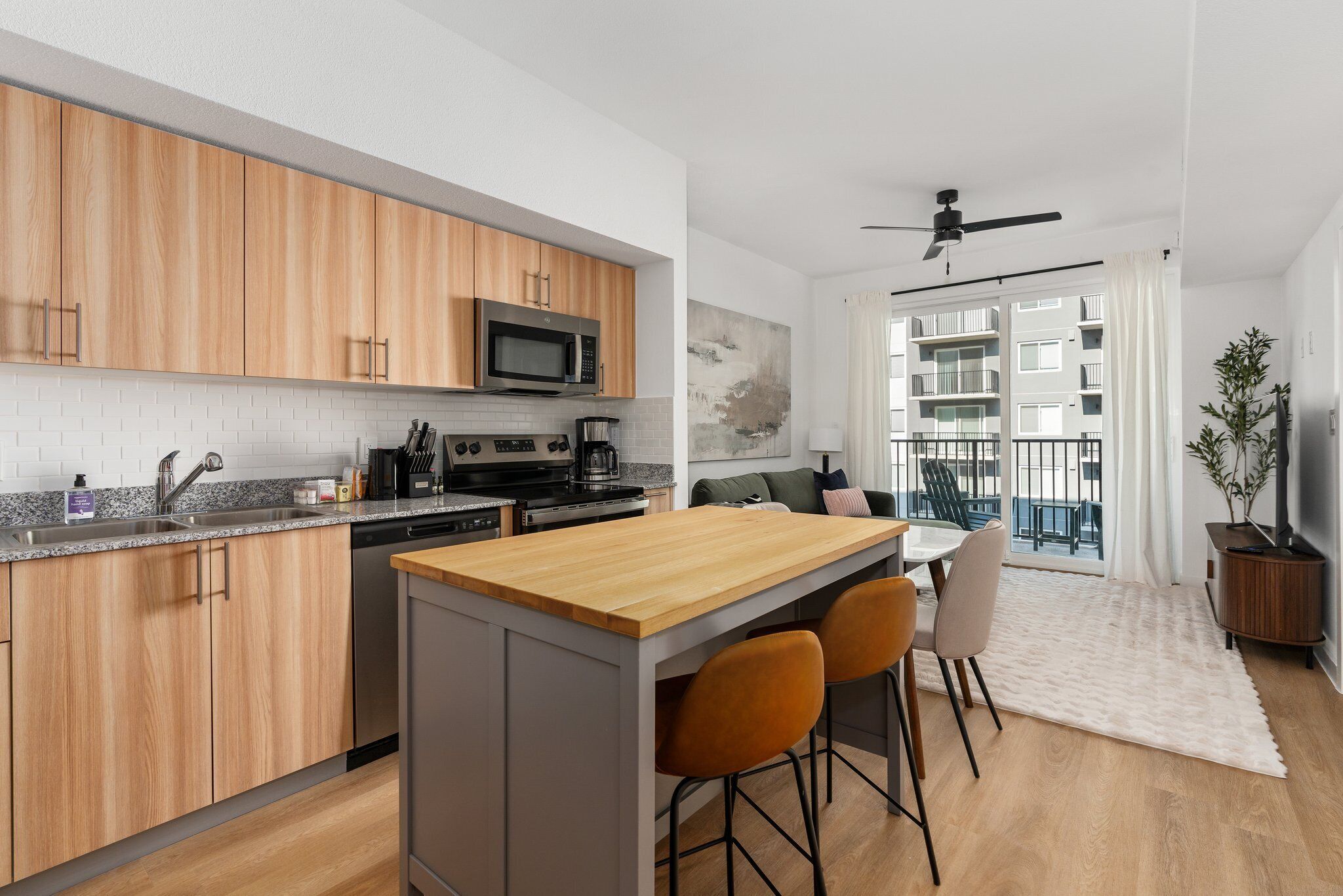 A modern kitchen with wooden cabinets, a microwave, and a dining area with a wooden table and two chairs.