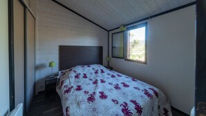 Un dormitorio con cama, mesita de noche, lámpara y ventana.