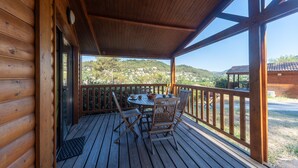Una terraza de madera con una mesa y sillas, con vistas a un paisaje pintoresco.