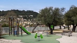 Un parque infantil con un tobogán, columpios y una zona de juegos verde.