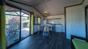 Una cocina compacta con electrodomésticos modernos, un comedor con mesa y sillas, y un amplio ventanal corredero que da a una terraza exterior.
