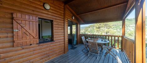 Une cabane en bois dotée d’une terrasse, d’une porte coulissante et offrant une vue sur le paysage.