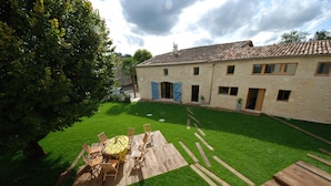A stone building with a tiled roof, a wooden deck, and a grassy lawn.