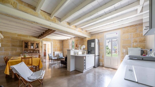 A spacious kitchen with a dining area, stone walls, and a large window.