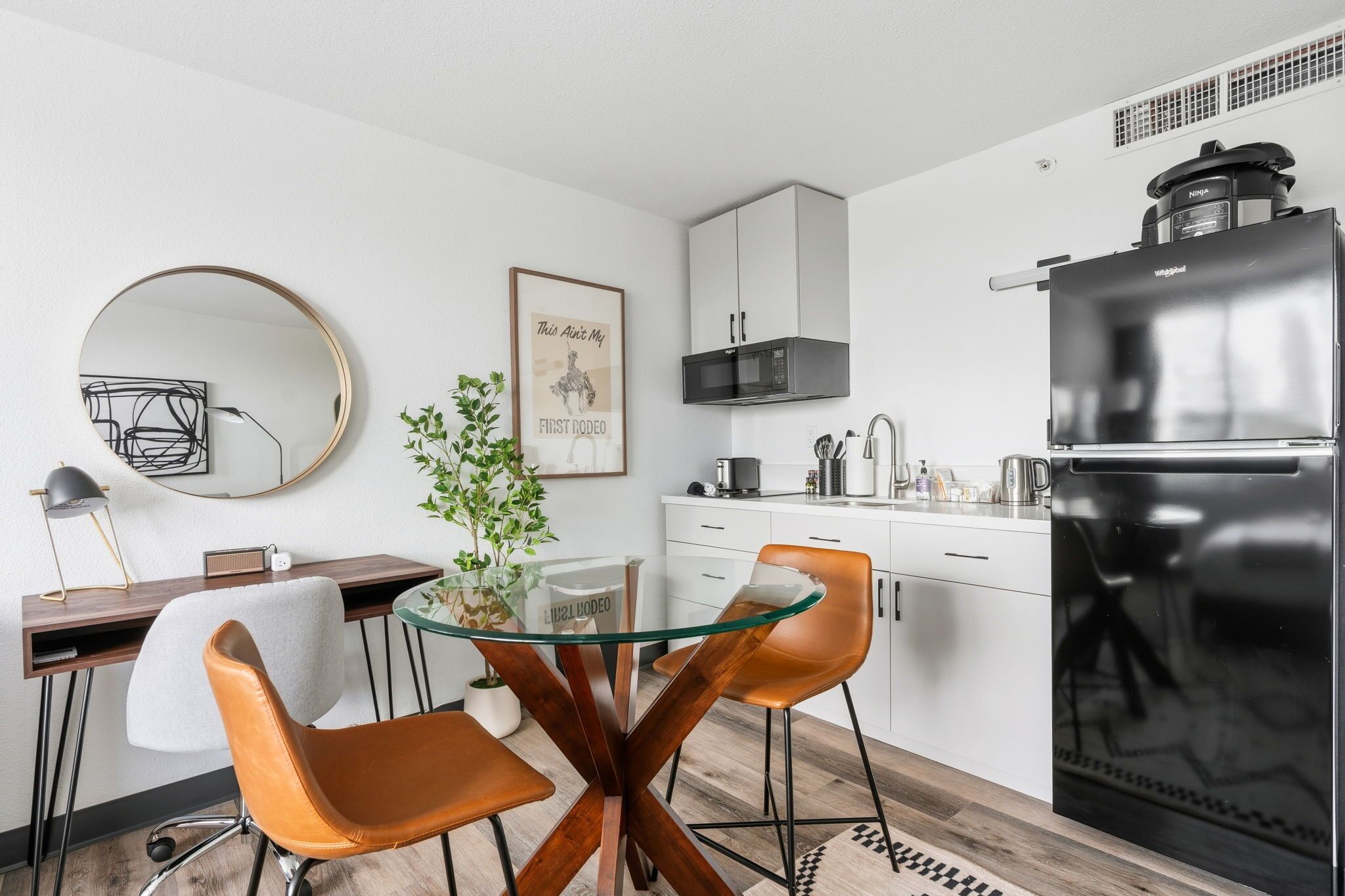 Une cuisine moderne équipée d’un réfrigérateur, d’un four à micro-ondes et d’un coin repas avec des chaises et une table.