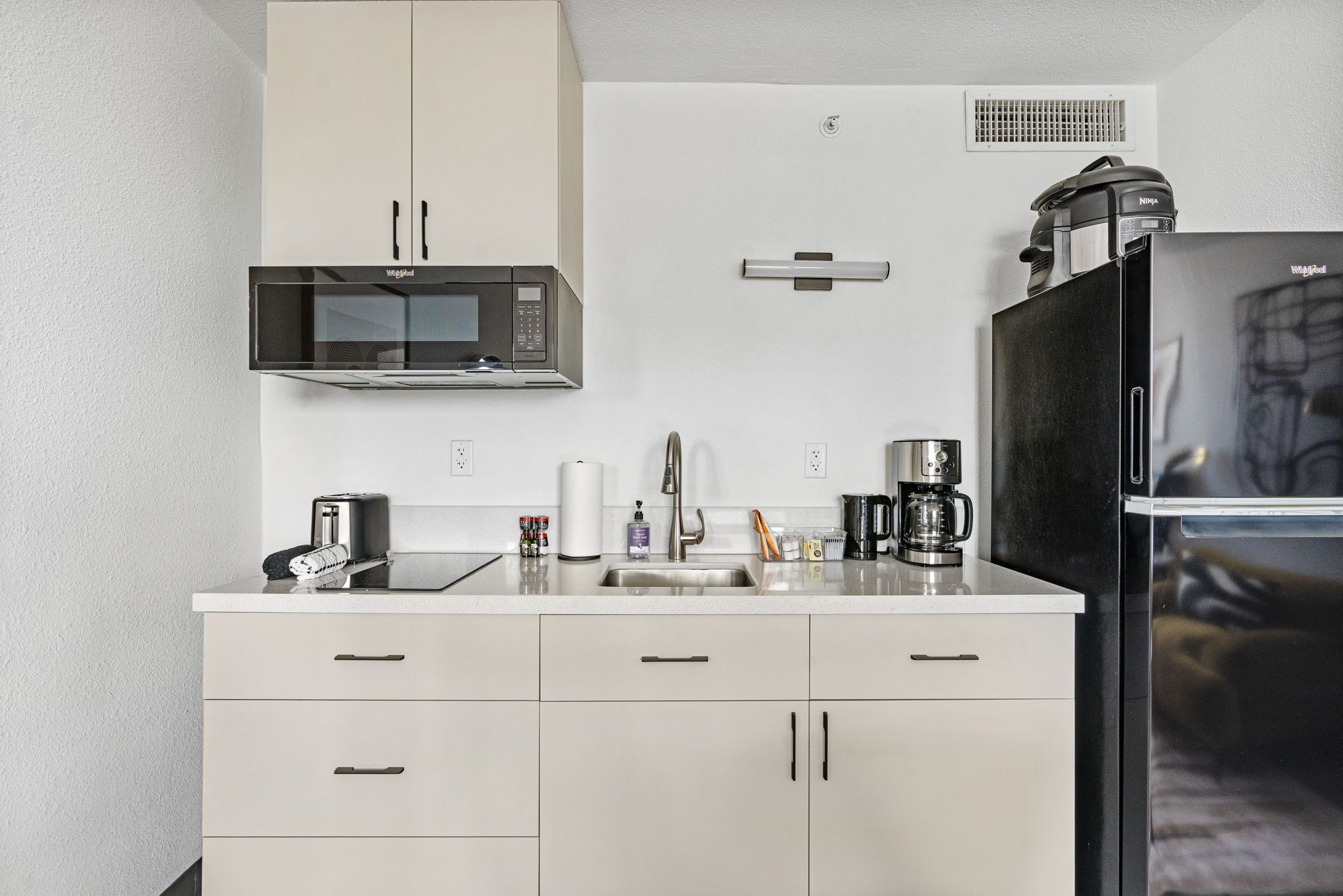 A modern kitchen with a microwave, coffee maker, and refrigerator.