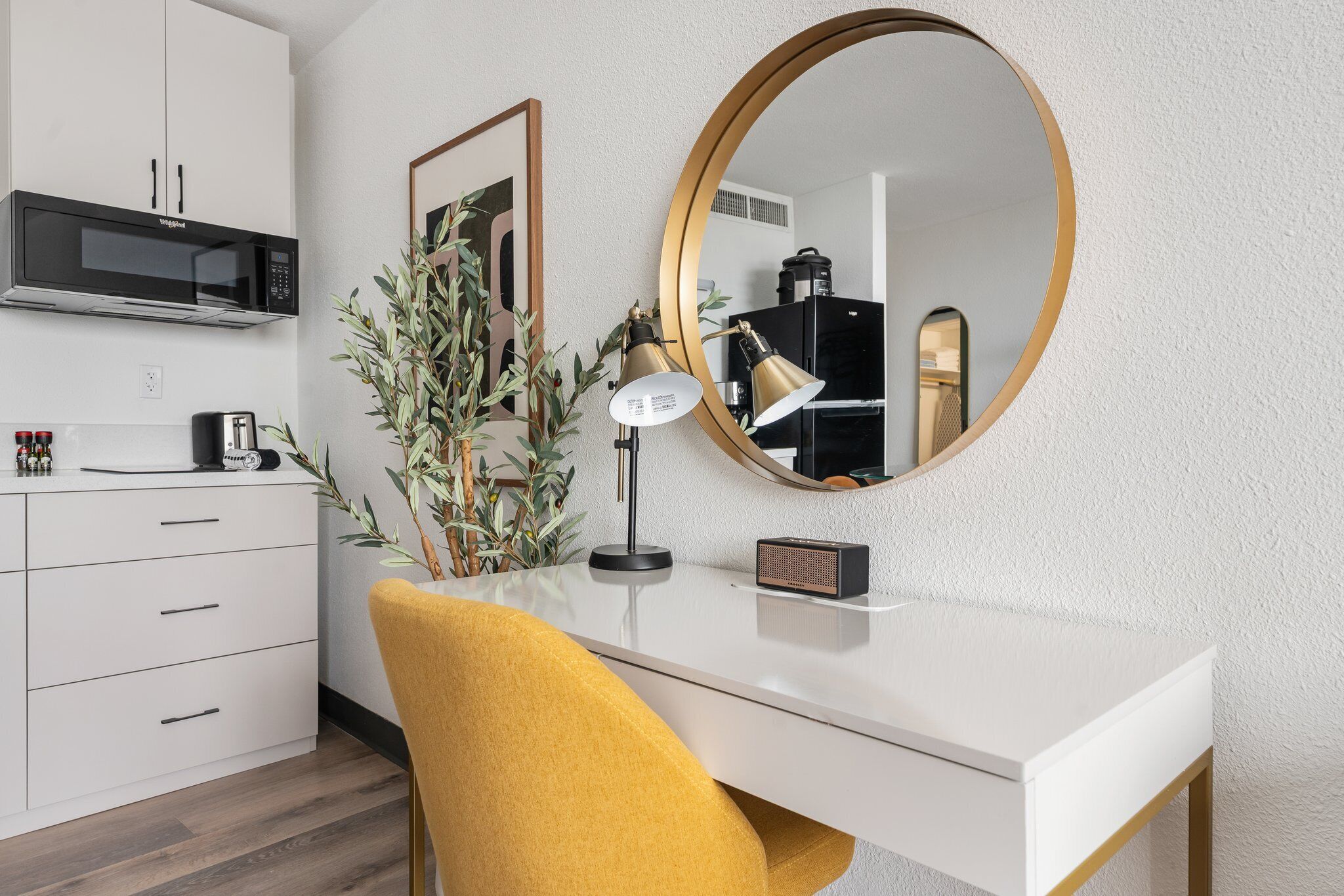 A modern kitchen with a microwave, a coffee maker, and a potted plant.