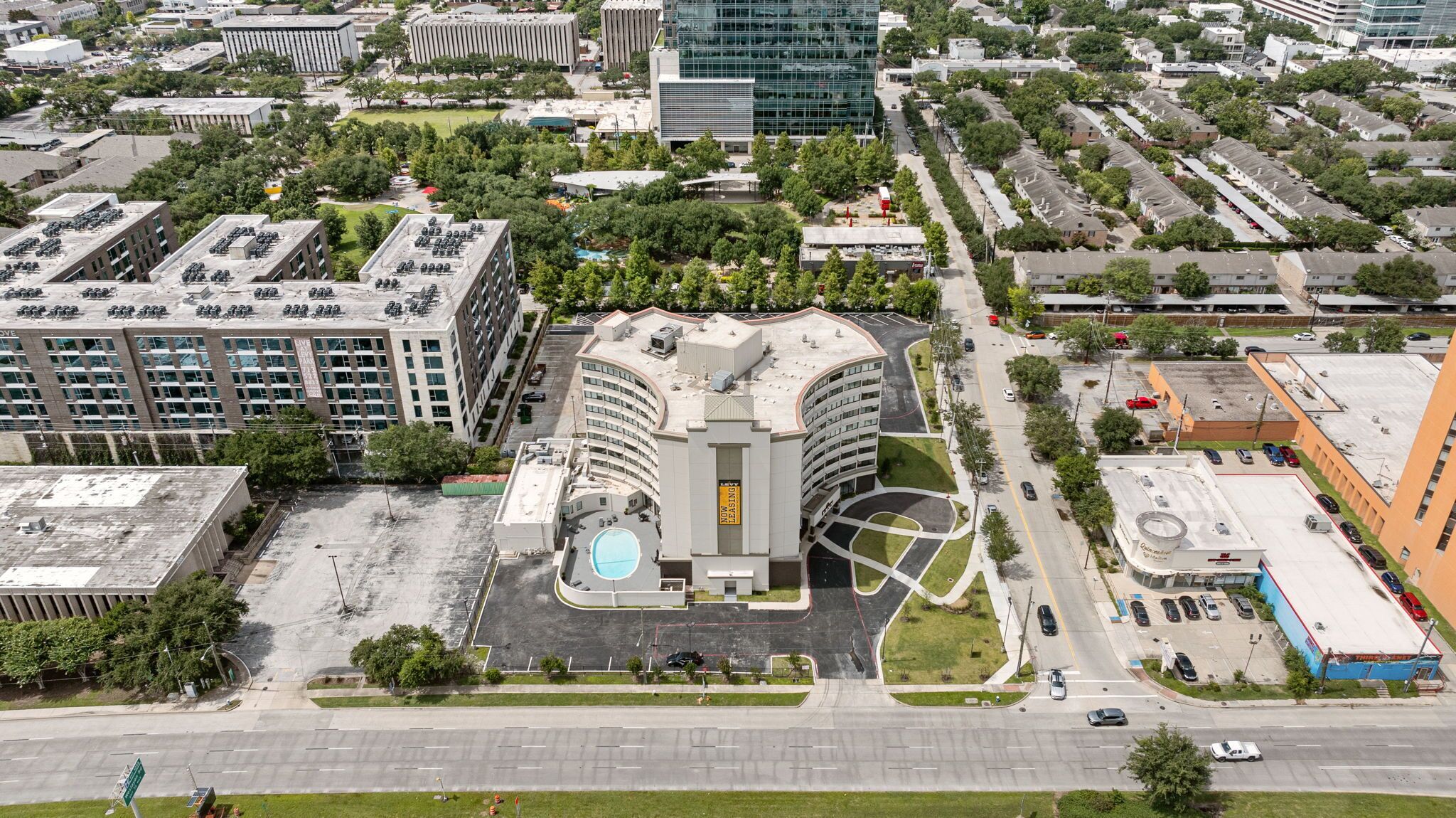 An aerial view of a multi-story building with a central courtyard, surrounded by parking areas and other buildings.