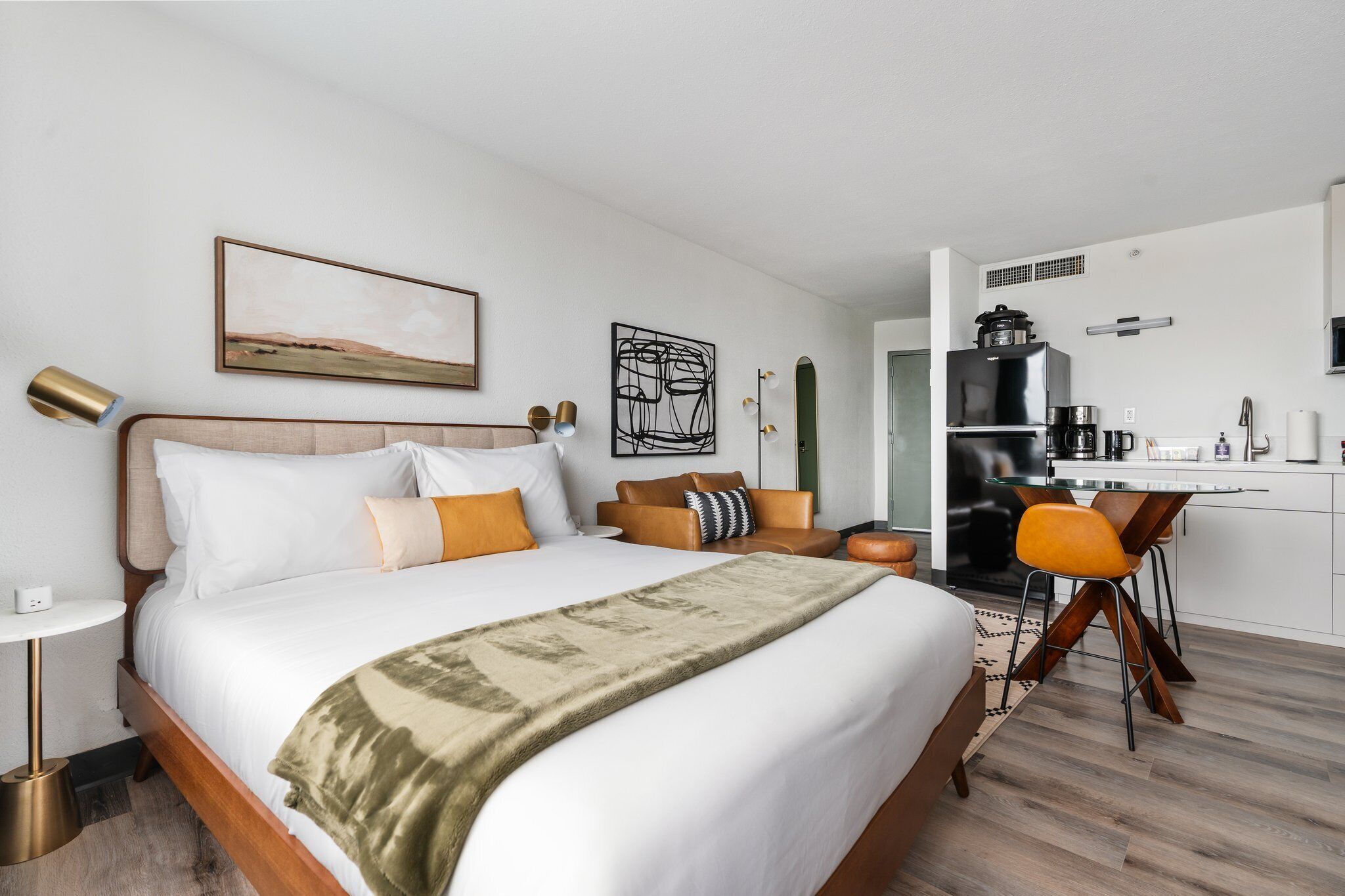Een moderne hotelkamer met een groot bed, een bureau en een kitchenette.