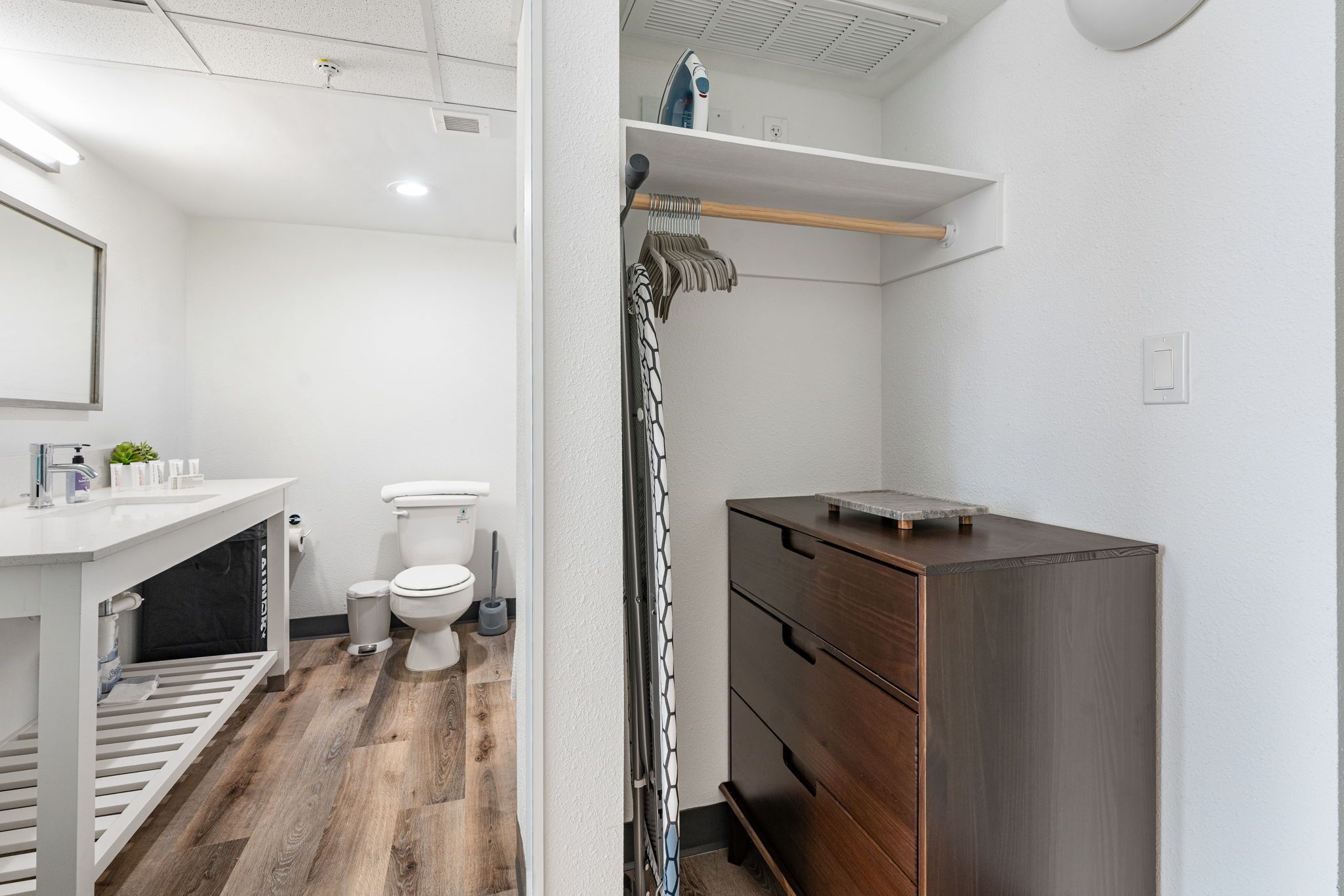 A modern bathroom with a white sink, toilet, and vanity with a wooden cabinet.