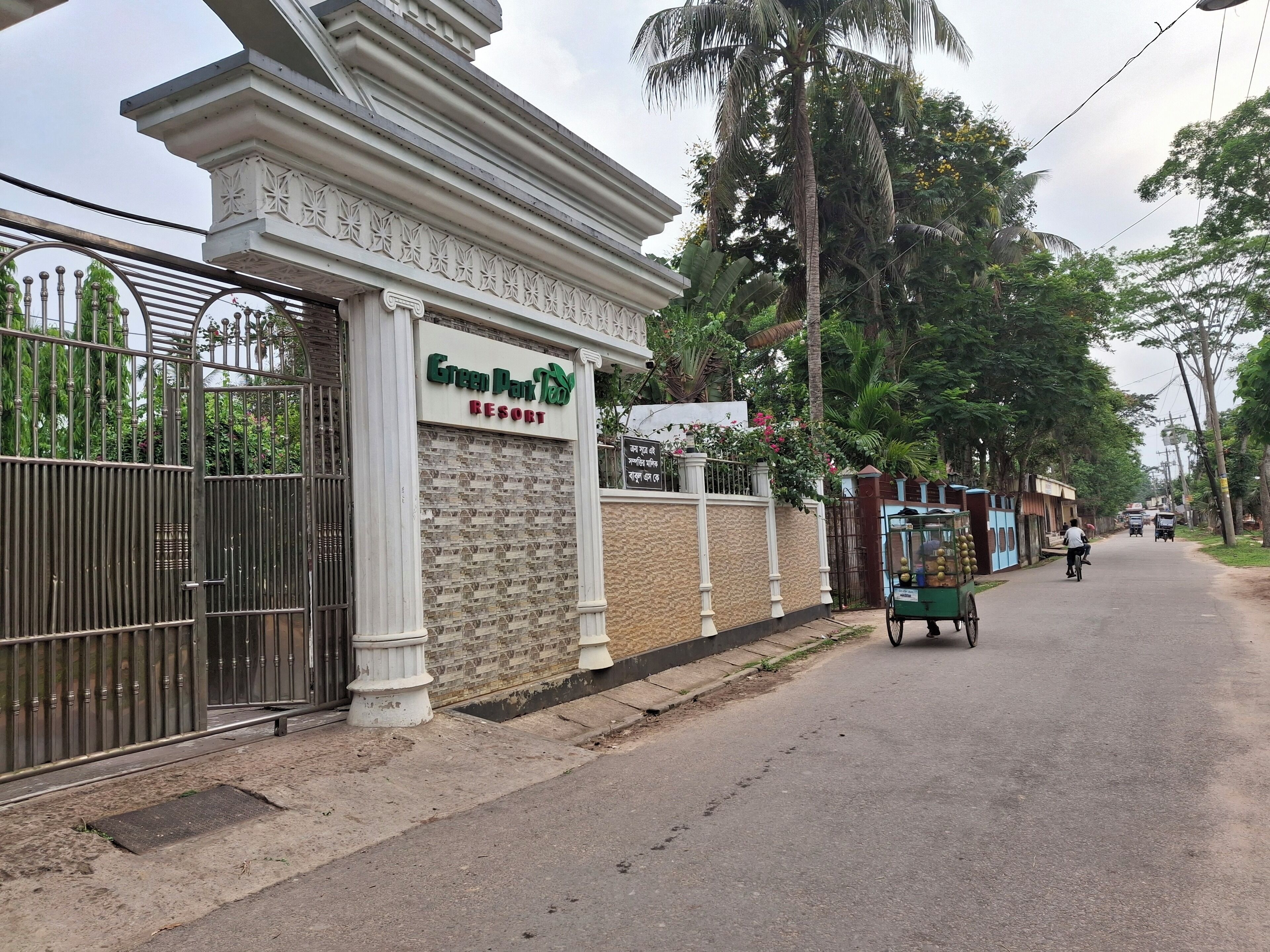 A gated entrance to Green Park Resort with a signboard and a decorative wall.