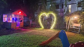Un terrain de jeux agrémenté d’une installation lumineuse en forme de cœur, d’un toboggan et d’un petit pavillon éclairé de lumière rouge.