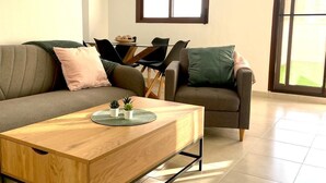 A modern living room with a wooden coffee table, two sofas, and a dining table.