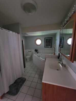 A bathroom with a bathtub, sink, toilet, and a shower curtain. - Sunny Dock Rentals LLC- Barefoot Beach Bungalow (Coral)