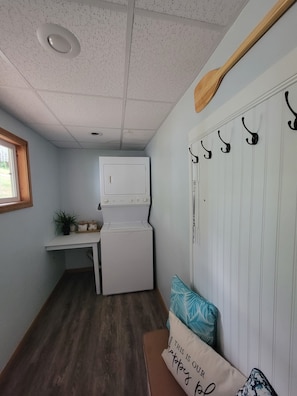 A laundry room with a washer and dryer, a small table with a plant, and a wall-mounted drying rack. - Sunny Dock Rentals LLC- Barefoot Beach Bungalow (Coral)