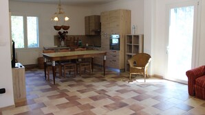 A spacious kitchen with a large island, wooden cabinets, and a dining area with chairs.