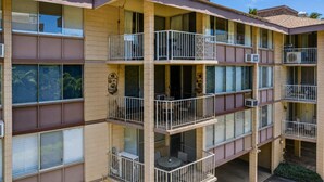A multi-story residential building with balconies, air conditioning units, and a tiled facade.