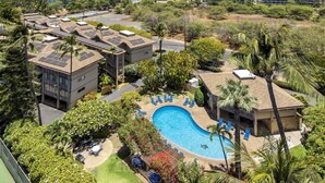 A resort with a swimming pool surrounded by lounge chairs and a view of the ocean.