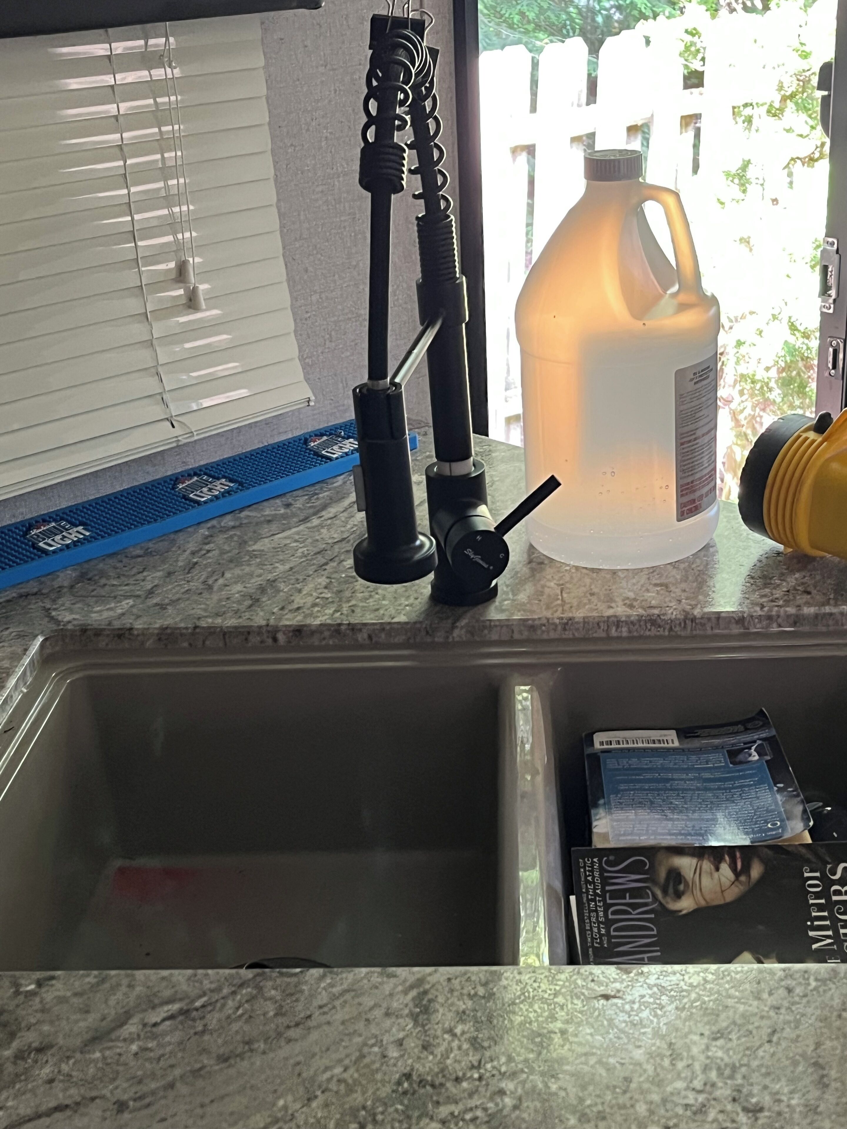 A kitchen counter with a sink, a large water jug, and a power tool.