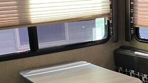 A train car with a small table, bench seating, and a window with blinds. -  Coleman camper you can pick it up and take it to your favorite campground (Berrien Springs)