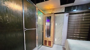 A hotel room with a sliding glass door, a wooden cabinet, and a bed with a white cover. - The Studio of Praise - by Zenbreak (Claxton Bay)