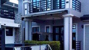 A modern two-story house with a balcony, large windows, and a garage. - The Studio of Praise - by Zenbreak (Claxton Bay)