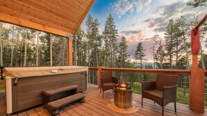 A wooden deck with a hot tub, a fire pit, and wicker chairs. - Shotski's Lodge - Secluded Ski-In/Out with Hot Tub, Wildlife and Views (Angel Fire)