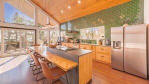 A modern kitchen with a large island, wooden cabinets, and a stainless steel refrigerator. - Shotski's Lodge - Secluded Ski-In/Out with Hot Tub, Wildlife and Views (Angel Fire)
