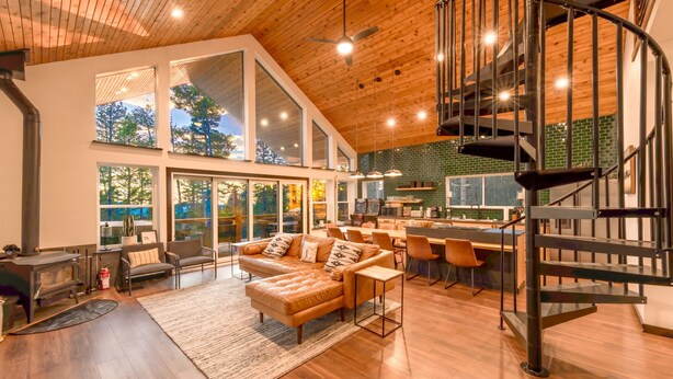 A spacious living area with a modern fireplace, a cozy sofa, and a dining area with a bar. - Shotski's Lodge - Secluded Ski-In/Out with Hot Tub, Wildlife and Views (Angel Fire)