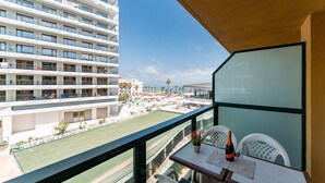 A balcony with a view of a hotel building, a pool area, and a tennis court. - MalagaSuite Sky & Sea Torremolinos (Torremolinos)