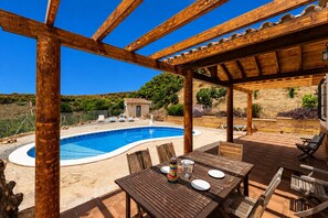 A wooden pergola over a swimming pool with a table and chairs, surrounded by a landscaped garden. - MalagaSuite Villa Rural Madeira (Algarrobo)