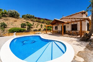 A swimming pool with a pergola and outdoor seating, surrounded by a landscaped garden and a hillside. - MalagaSuite Villa Rural Madeira (Algarrobo)