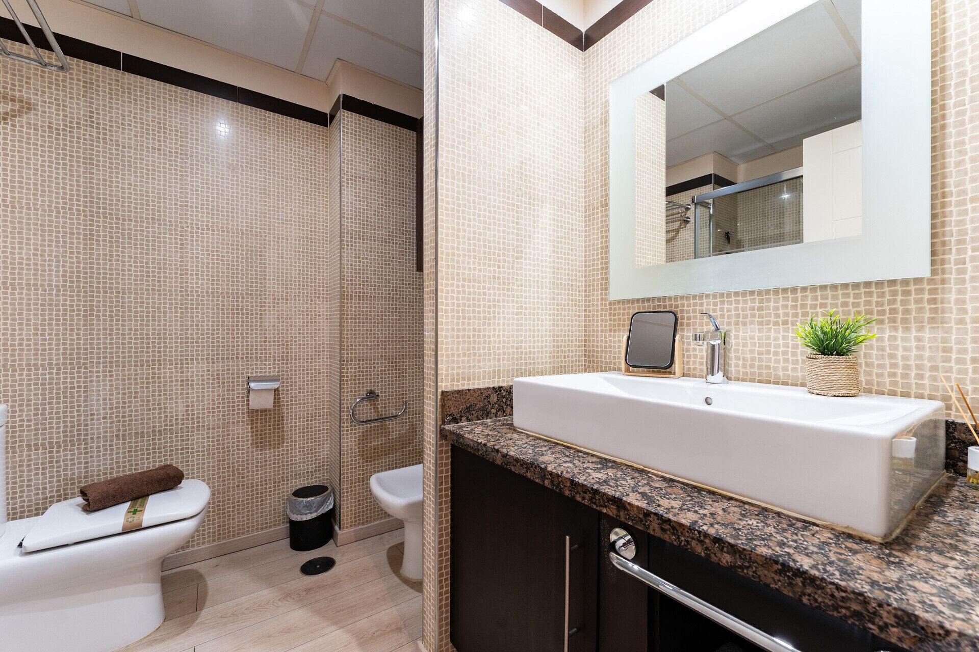 Un baño moderno con un espejo grande, un lavabo blanco y una zona de ducha.