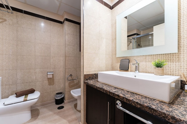 A modern bathroom with a large mirror, a white sink, and a shower area.