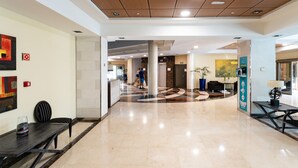 Un vestíbulo amplio con piso pulido, un mostrador de recepción y una zona de estar con una mesita de café.