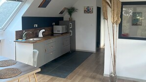 A modern kitchen with a dark blue accent wall, stainless steel appliances, and a wooden countertop.