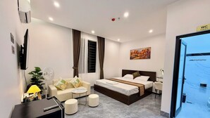 A modern hotel room with a bed, a sofa, a small table, a desk, and a TV. - Moc Hotel Hung Yen (Nguyen Van Linh)