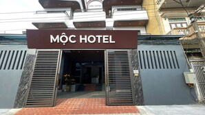 The entrance of MÔC HOTEL with a modern facade, metal shutters, and a visible staircase leading to the entrance. - Moc Hotel Hung Yen (Nguyen Van Linh)