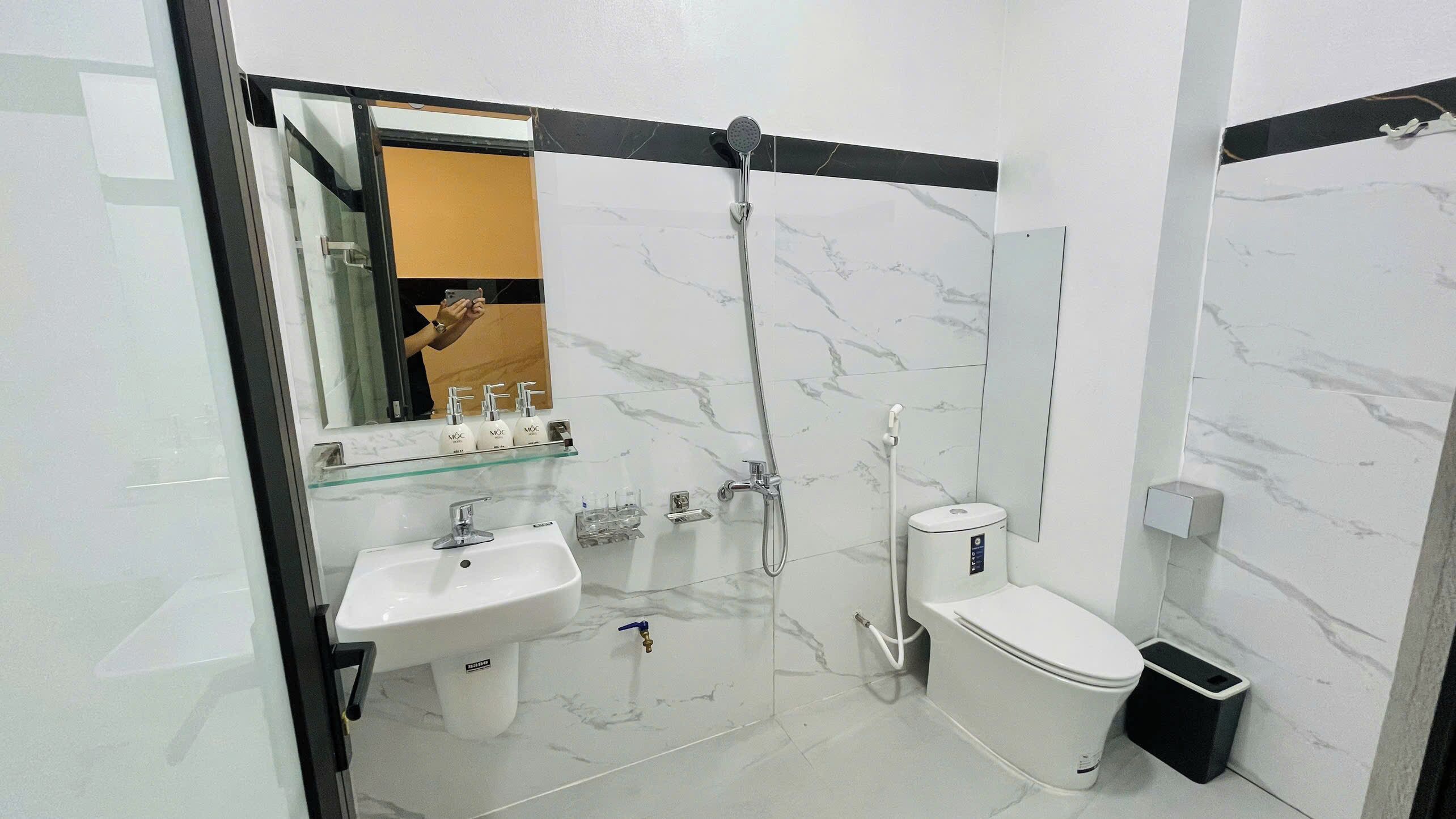 A modern bathroom with a glass shower enclosure, a white sink, and a toilet.