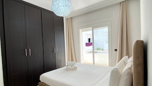 A bedroom with a bed, a wardrobe, a lamp, and a view of the outside.
