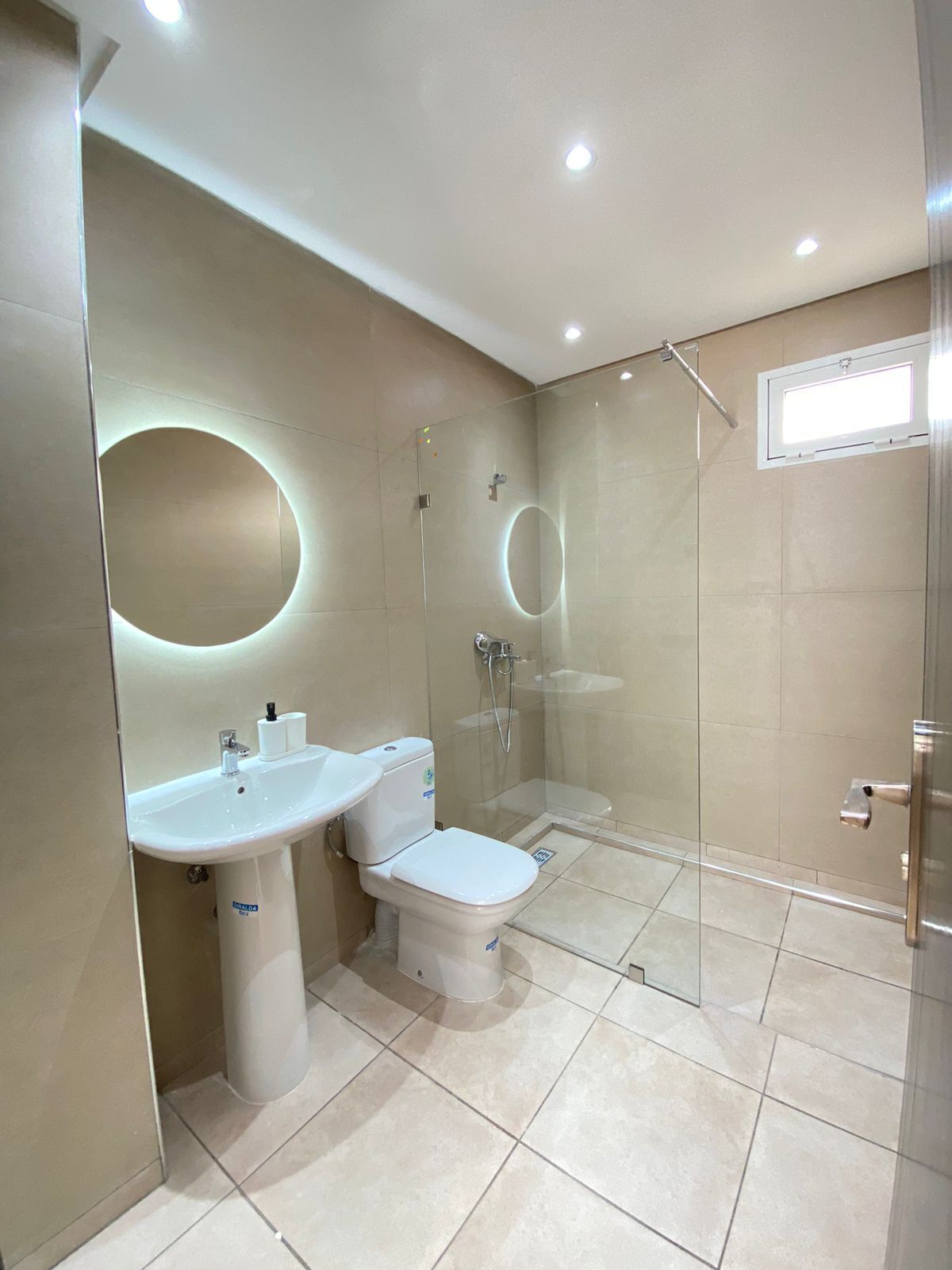 A modern bathroom with a toilet, sink, and glass-enclosed shower.