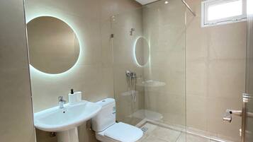 A modern bathroom with a toilet, sink, and glass-enclosed shower.