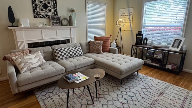 A living room with a sectional sofa, a coffee table, a fireplace, and a large window with blinds. - Rice Village Retreat, World Cup 2026 (Houston)